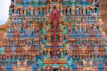 Fototapeta na wymiar Old south indian temple in close up with full architecture details. Multi colour temple tower in south India surrounded by mountains and rocks..