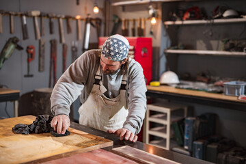 Male carpenter working on old wood in a retro vintage workshop.