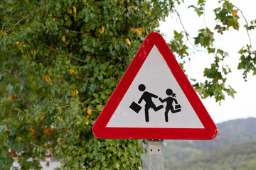 señal de tráfio advirtiendo de peligro por zona escolar - obrazy, fototapety, plakaty