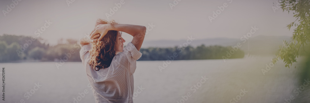 Wall mural beautiful young relaxed woman in white blouse enjoying nature breathing fresh air while standing wit