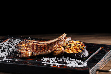 Side view on grilled beef steak with vegetables and salt