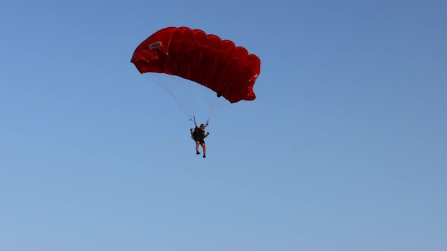Parachute on the blue sky. Parachutist is flying slowly down with an open parachute. Skydiving, gliding, parachute jump