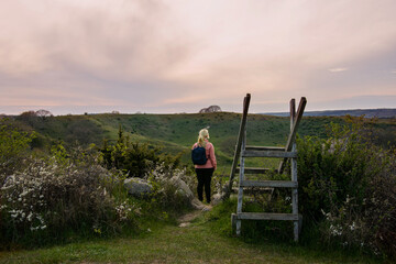 Woman hiking during sunset in the countryside landscape in Skåne, Sweden. Woman wearing outdoor...
