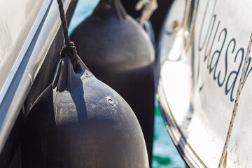 Close up of two marine inflatable fenders on a boat for protection, on a sunny day