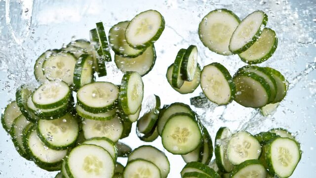 Super slow motion of fresh sliced cucumber with water splashes flying in the air. Filmed on high speed cinema camera, 1000 fps.