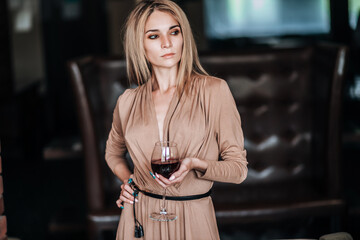 A woman holds a glass of red wine in a restaurant.