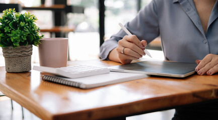 Close up business accountant using digital tablet for calculate finance on wooden desk