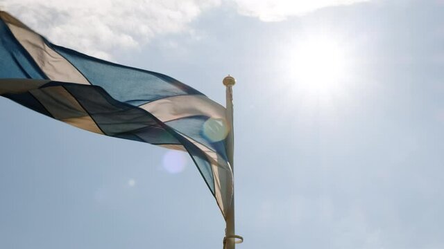 Slow motion view of the flag of Scotland, also known as St Andrews Cross, flying against a bright blue sky