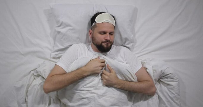  Top view of caucasian bearded man going to bed, sleeping and waking up in light room. High angle shooting. Attractive guy going to and gettting out of bed. Good morning calm awakening 4k 