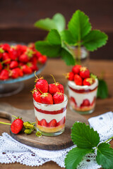 Strawberry dessert in a glass with a decor of cut strawberries standing on a wooden background