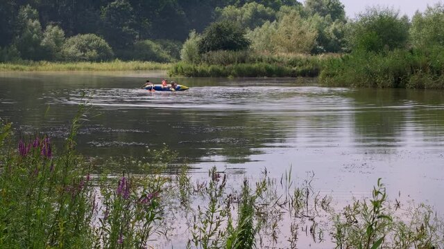 People paddle rubber dinghy, at lake