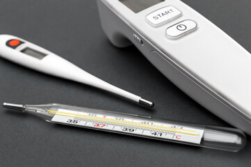 Different type of thermometers on grey background. Infrared, electronic and mercury thermometers.