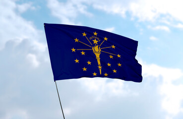Flag of Indiana in front of blue sky, realistic 3D rendering