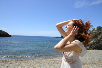 Fototapeta na wymiar Happy woman touching hair in a windy beach day