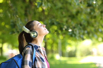 Student wearing headphones breathing fresh air in a campus