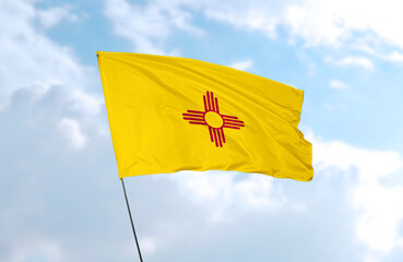 Flag of New Mexico in front of blue sky, realistic 3D rendering