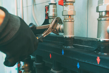 Plumber screwing nut of pipe in the heating system in the boiler room