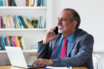 Mexican senior businessman talking with customer at phone