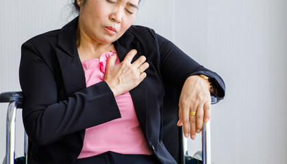 Senior woman sitting on wheelchair suffering from sudden heart attack and hold chest. Concept of emergency health care and affected from  Cardiopulmonary Resuscitation, heart problem