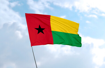Fototapeta na wymiar Flag of Guinea-Bissau, realistic 3d rendering in front of blue sky