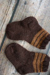 Small and warm newborn socks made of woolen yarn, on dark wooden background