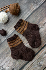 Obraz na płótnie Canvas Small and warm newborn socks made of woolen yarn, on dark wooden background
