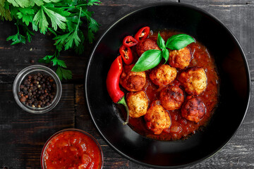 Chicken meatballs with basil and tomato sauce. Dark background. Copyspace. Meatballs with tomato and chili. Top view