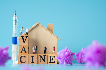 miniature doctor , patient , home , purple virus and syringe with Wooden cubes with words ''vaccine" on blue background