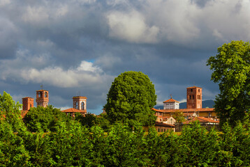 Fototapeta na wymiar Lucca charming historic center skyline with medieval towers rises above surrounding anciet walls park trees