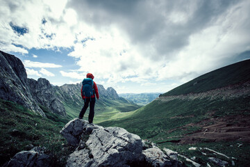 Successful woman hiking on sunset alpine mountain peak