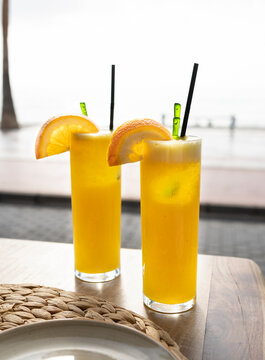 Two Refreshing Orange Juices In Beach Background