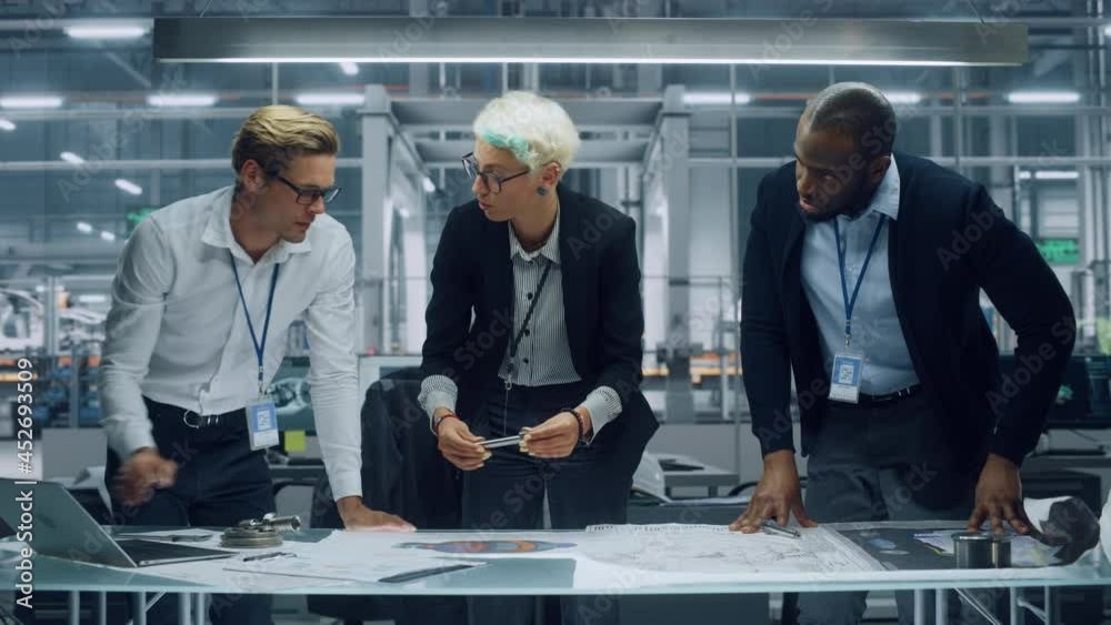 Poster Young Diverse Team of Automotive Engineers Working in Office at Car Factory. Industrial Designer Talks About Electric Engine Parts with Colleagues, Discussing Technical Blueprint for Mobility Project.