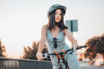 Chica joven adolescente montada en una bici en la carretera junto a las señales y el sol
