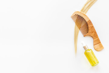 Hair essential oil with wooden comb and blond curl of hair