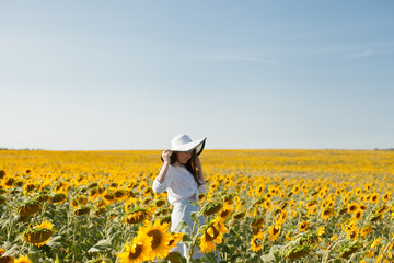 Fototapeta premium woman in a hat in a field of sunflowers