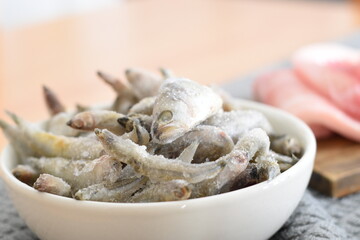 frozen sardines in a white bowl held by a woman's hands