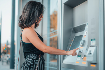 Mujer adulta utilizando el cajero automático de la estación de tren para pagar su tiquet