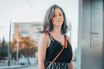 Muchacha joven sonriente en la estación del tranvía esperando un nuevo tren para viajar