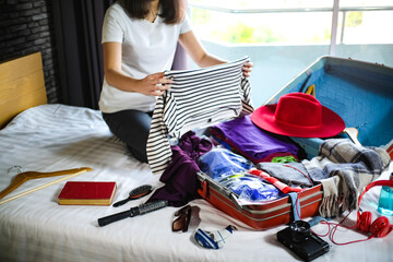 Woman packing suitcase on bed for a new journey packing list for travel planning, preparing vacation Book Now Traveling Transportation