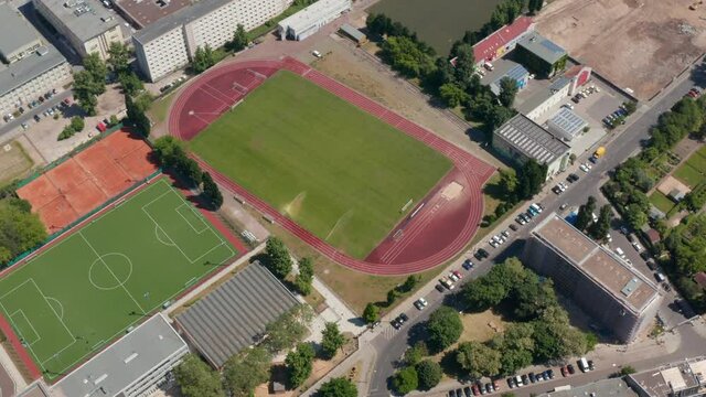Backwards reveal of sports centrum. Aerial view of area for doing various sports, football pitch, tennis courts and athletic sports field. Berlin, Germany