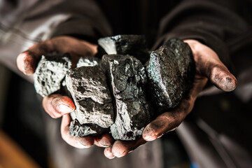 Coal mining : coal miner in the man hands of coal background. Picture idea about coal mining or energy source, environment protection. Industrial coals holding on hands. Volcanic rock. Panorama photo - obrazy, fototapety, plakaty