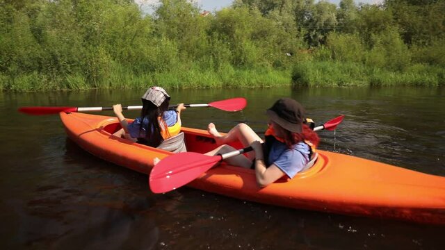 Kayaking on the River. Girls tourists kayaking down the river, teamwork
