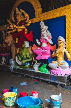 A Hindu festival idol workshop with sculptures under construction with freshly applied paint. Various colorful paints in buckets for painting and preparation for religious worship.