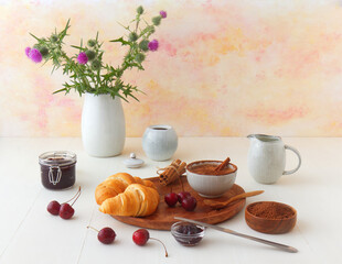 Tasty healthy food, breakfast, brunch or just dessert. Freshly baked croissants with jam from latest cherry harvest and hot cocoa. White wooden table background.