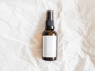 Mockup for care cosmetic product - amber bottle with white labels on crumpled white paper...