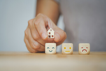 senior human hand holding mini house over happy face  for home sweet home, wellness, wellbeing and  mental heath concept