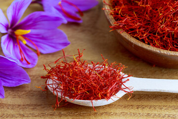 Saffron stamens in a wooden spoon. On the blossomed flower three red stamens which tear off and dry...