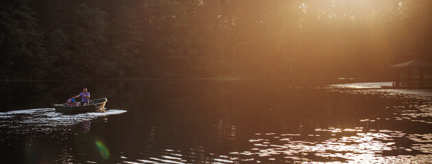 dad and son are sailing on a boat on the lake for fishing