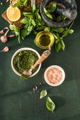 Obraz na płótnie Canvas Pesto sauce in bowl with ingredients on rustic green table. Traditional Italian pesto recipe for making fettuccine, pasta, bruschetta.