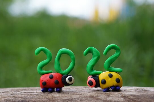 Two ladybugs and the number 2022 from plasticine close-up.